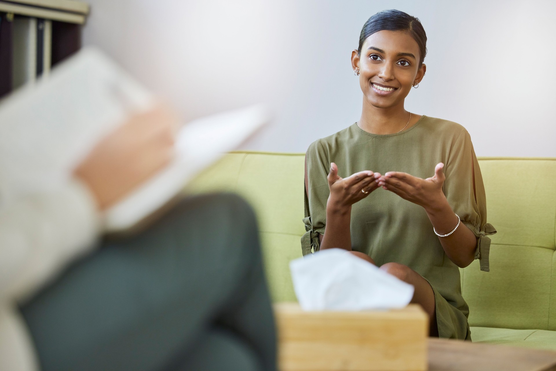 Therapy, psychology and young woman talking of help, support or mental health solution and therapist writing notes. Counseling service, progress and psychologist with indian patient, client or person