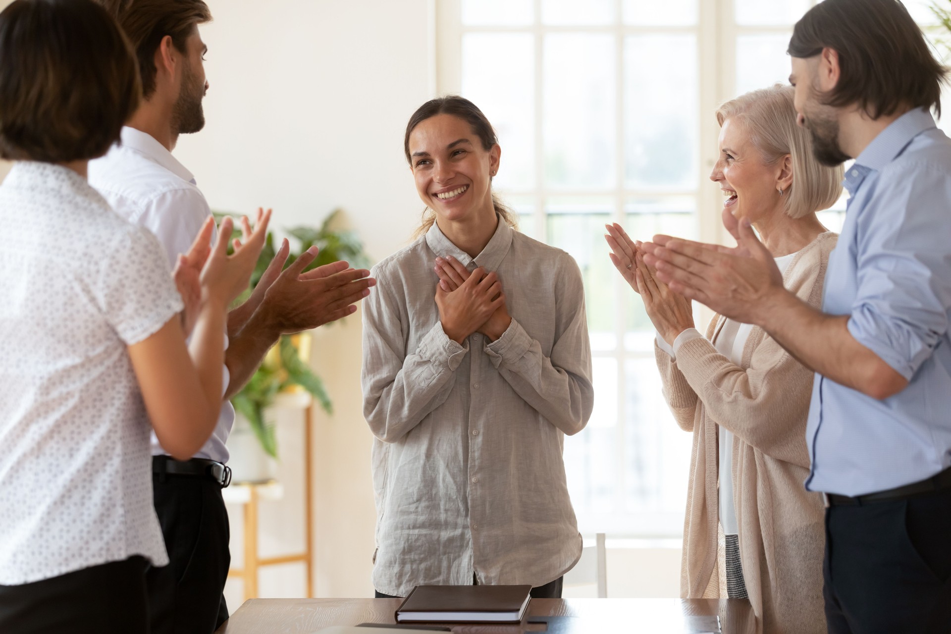 Staff encouraging mixed-race newcomer employee at meeting